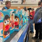 Sequim Gazette photos by Matthew Nash
Cody Avila with Walmart helps ring up Mr. Potato Heads, plush elephants and about 600 other toys for Toys for Tots volunteers Guy Iredale, Ron Zimmermann and Eric Miner.