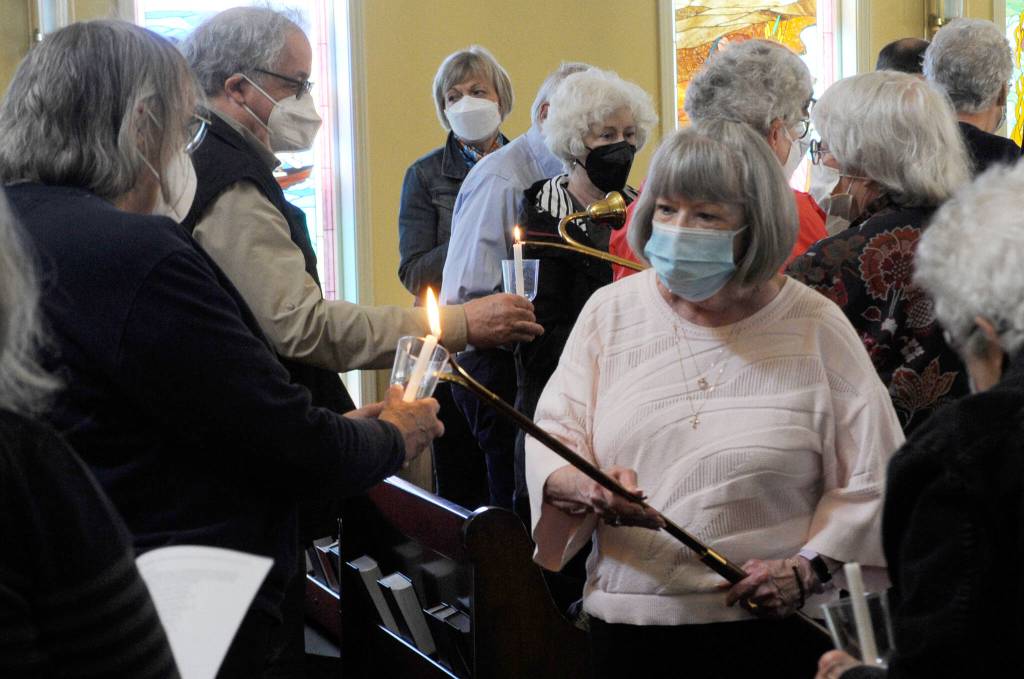 Sequim Gazette photo by Matthew Nash/ Pat Rublaitus helps light candles for a candlelight prayer service on May 27 inside St. Lukes Episcopal Church in Sequim, honoring victims of the Robb Elementary School shooting in Uvalde, Texas. About 40 people attended to pray and sing for the teachers and students and their families.