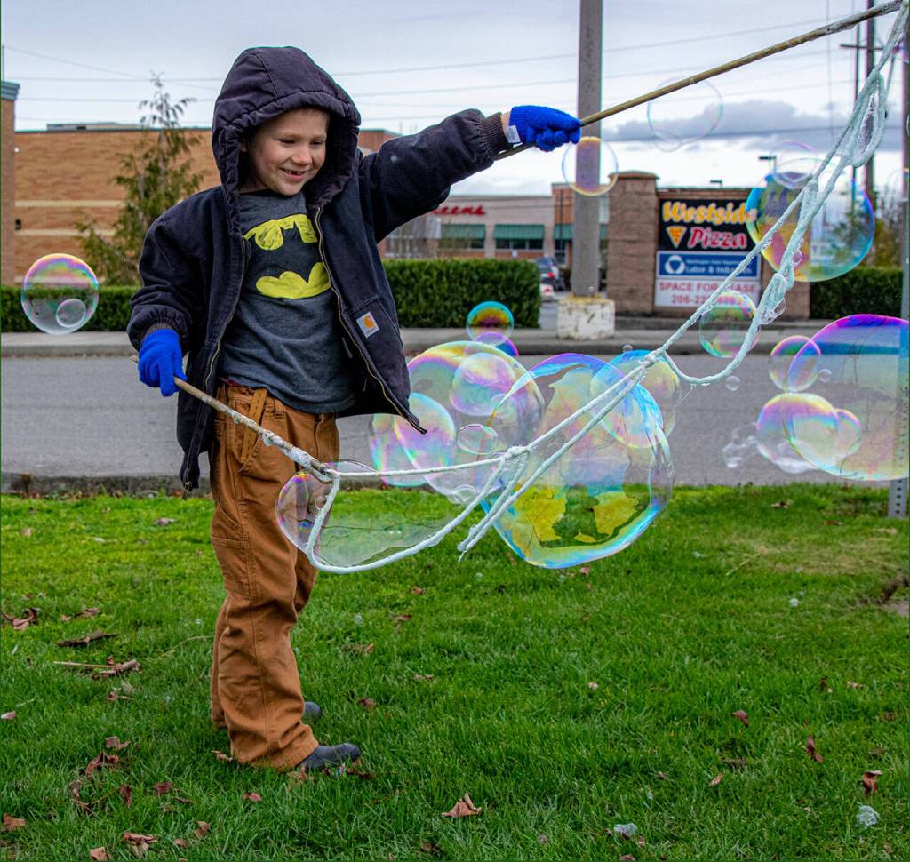 Sequim Gazette photo by Emily Matthiessen/ Jasper Davis produces bubbles from a homemade bubble solution, cotton rope, and dowels at the Sequim Safeway Plaza in March.