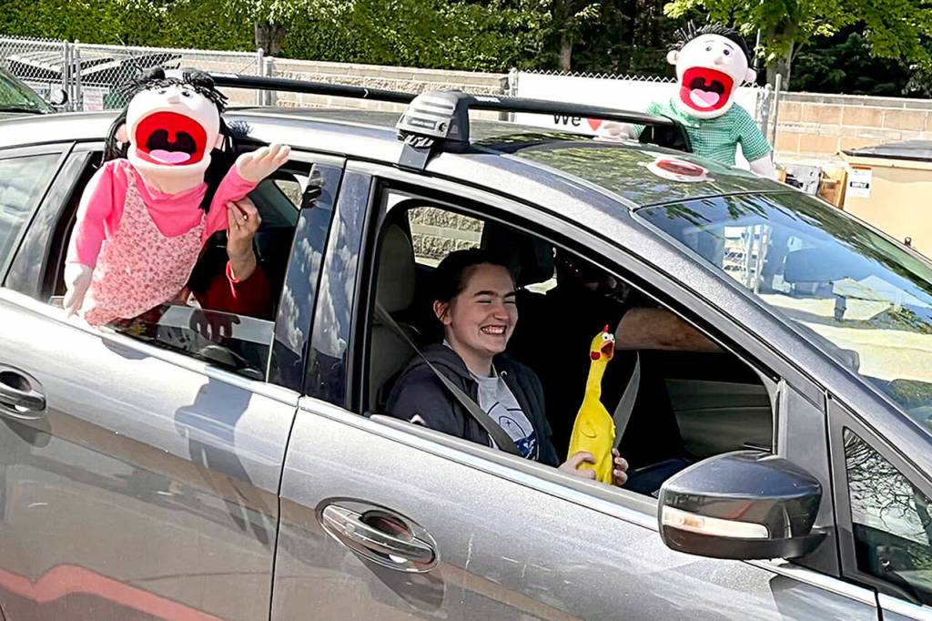 Sequim Gazette photo by Matthew Nash/ In June, Sequim Middle School student Emma Gilliam smiles as puppets  held by her parents Glenn and Kecia  cheer for her during the drive-through event celebrating eighth-graders moving onto high school.