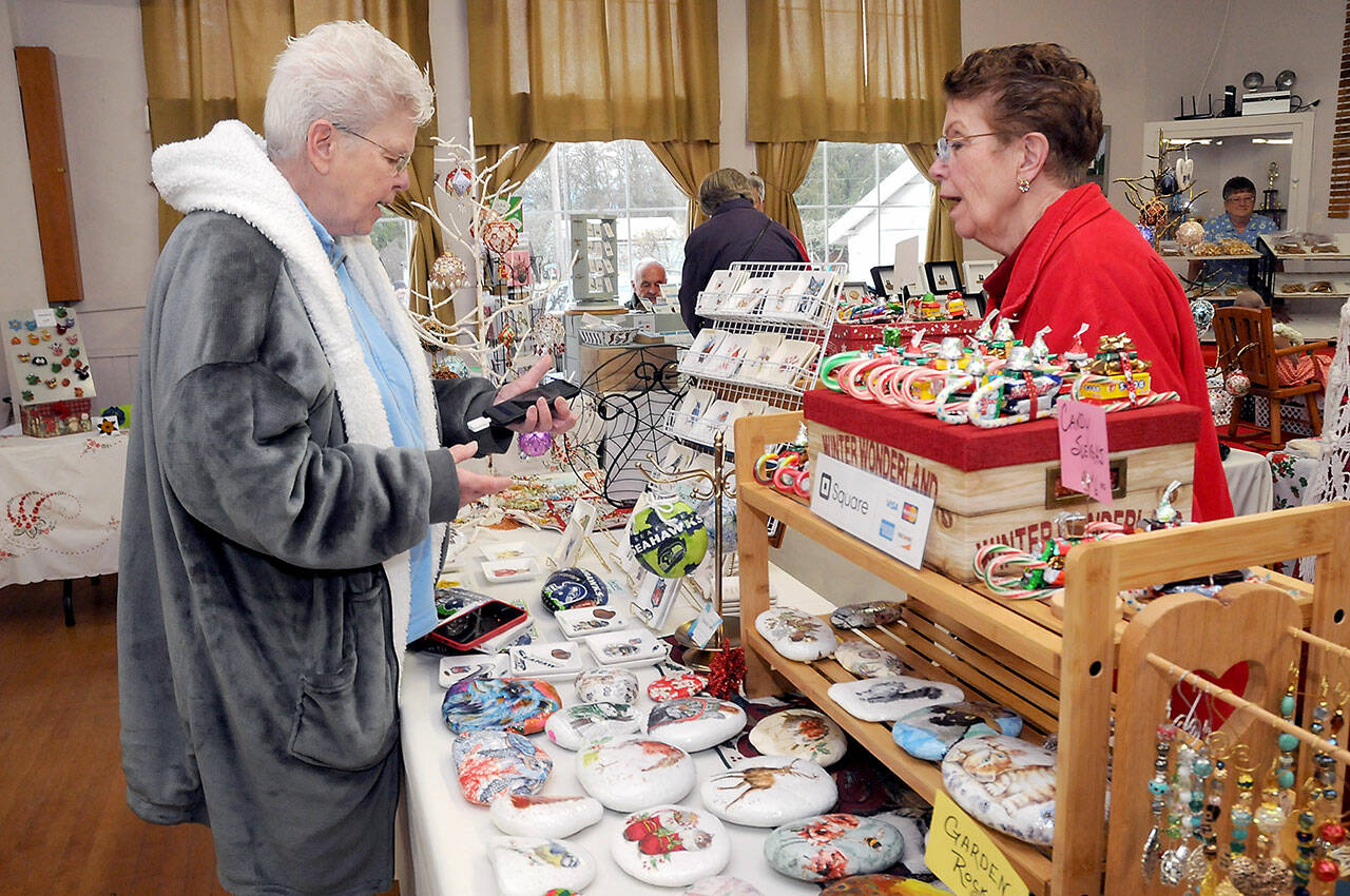 Photo by Keith Thorpe/Olympic Peninsula News Group
Sandie Kiehl of Sequim, left, makes a purchase from Pat Snyder of Sequim-based China Cat Creations during the Homemade Christmas Craft Fair at the Sequim Prairie Grange near Carlsborg on Dec. 3. The event featured dozens of vendors with a wide variety of holiday gifts and gift ideas created by local artisans.