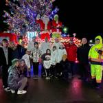 Sequim Gazette photo by Matthew Nash/ Volunteers gather by Sequims downtown Christmas tree at the corner of Sequim Avenue and Washington Street for the last night of Santas Toy and Food Brigade on Dec. 9.
