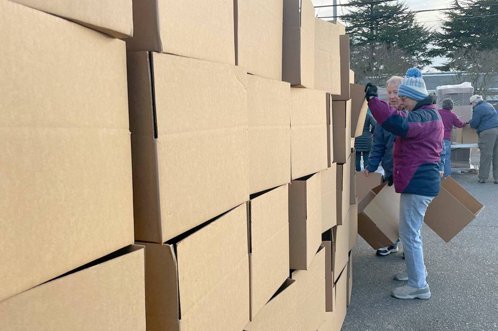 Sequim Gazette photos by Matthew Nash
Leslie Bagwell and Mark Pekar carefully stack some of the 850 boxes they and other volunteers with Sequim Seventh-day Adventist Church made and filled with food for Christmas meal boxes distributed in Carrie Blake Community Park on Dec. 16.