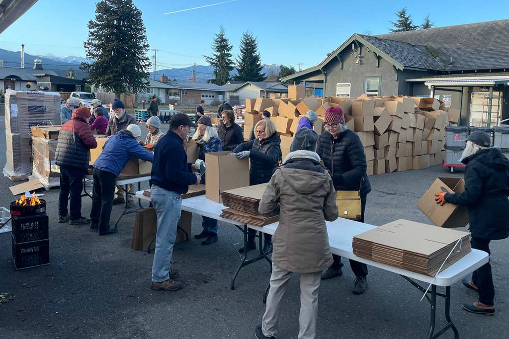 Volunteers with Seventh-day Adventist Church make and later fill boxes with food for Christmas meal boxes distributed in Carrie Blake Community Park on Dec. 16.