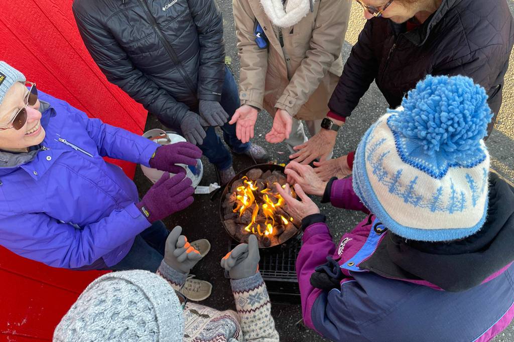 Sequim Gazette photo by Matthew Nash/ Sequim Food Bank volunteers with Seventh-day Adventist Church gather around a heater in-between making and stacking boxes and filling them with hearty meals for Christmas to be distributed at Carrie Blake Community Park.