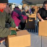 Sequim Gazette photo by Matthew Nash/ Bill Needham, a volunteer organizer for Sequim Seventh-day Adventist Church at Sequim Food Bank, and Chris Torell with Sequim Food Bank pack boxes on Dec. 15 for distribution in Carrie Blake Community Park for Christmas.