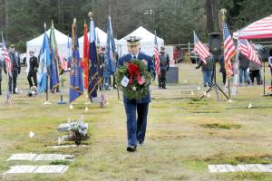 Cmdr. Brian Tesson, commanding officer of the U.S. Coast Guard Cutter Active, carries a wreath for the grave of Coast Guard veteran Harold Hanusa, who served during World War II, during Saturday's Wreaths Across America ceremony at Mount Angeles Memorial Park in Port Angeles. The event, part of a national initiative to honor veterans of military service, saw individual branches of the military recognized during the ceremony followed by the placement of more than 2,300 wreaths for servicemen and women at six cemeteries across the North Olympic Peninsula. (Keith Thorpe/Peninsula Daily News)