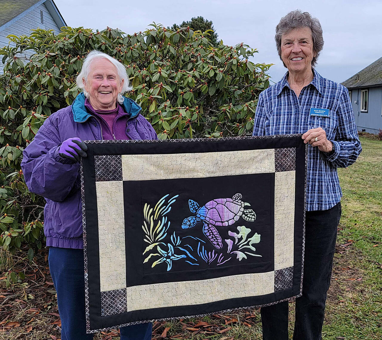 Photo by Carmi Standish/Sequim Bay Yacht Club 
Pam Cameron, left, receives The Spirit of Honu from Sue Baden in the raffle held by Sequim Bay Yacht Club.