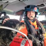 Petty Officer 3rd Class Austen Marshall, an avionics electrical technician and a flight mechanic at Coast Guard Air Station Port Angeles, sits near a dog his aircrew rescued from a grounded sailing vessel near Vancouver Island, British Columbia. The aircrew rescued one person and two dogs from the vessel. (U.S. Coast Guard courtesy photo)