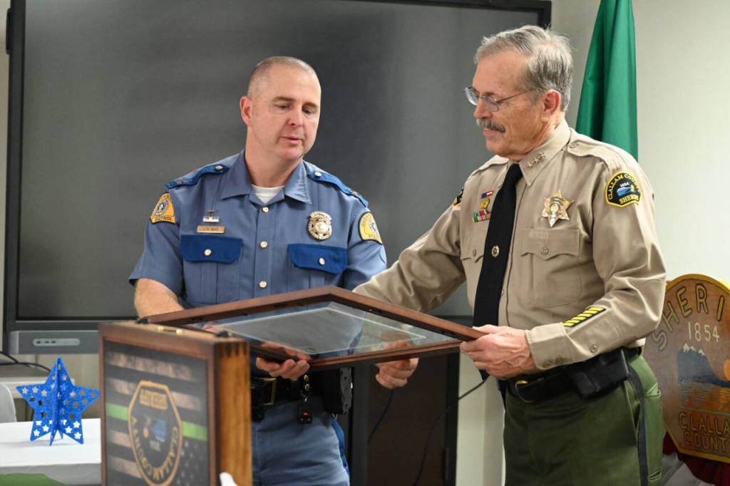 Sequim Gazette photo by Michael Dashiell / Outgoing Clallam County sheriff Bill Benedict, right, accepts a framed tribute from Washington State Patrol Sgt. James Mjor at a retirement party on Dec. 27 in Port Angeles.