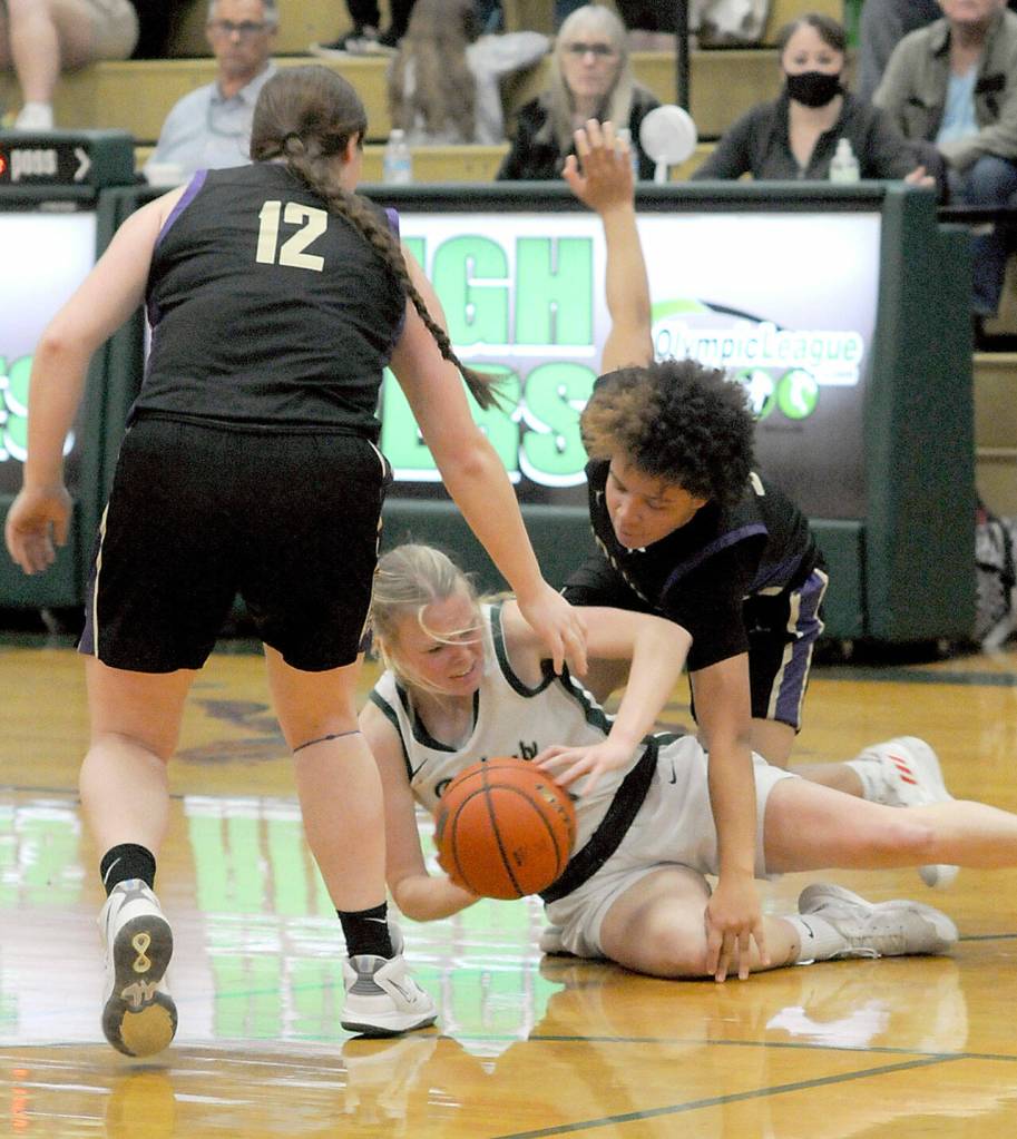 Port Angeles Anna Petty, center, tries to get rid of the ball from the floor as Sequims Sammie Bacon, left, and Bobbie Mixon close in during a key Olympic League matchup in Port Angeles on Jan. 10.