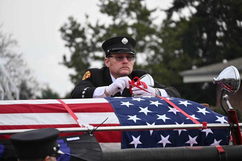 Sequim Gazette photo by Michael Dashiell
Scott Dickson, longtime firefighting partner of Capt. Charles Chad Cate, removes straps securing Cates casket at a memorial Saturday afternoon for the firefighter who was found deceased while on shift on Jan. 12.
