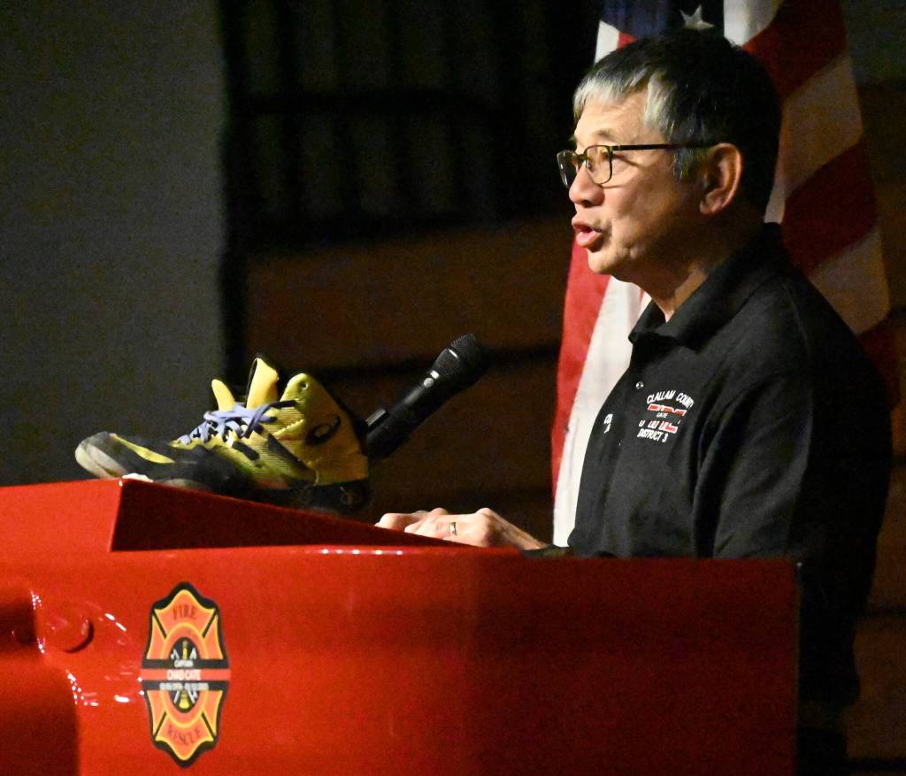Sequim Gazette photo by Michael Dashiell
Steve Chinn, Charles Chad Cates coaching partner and his former head coach, talks about Cate at a Jan. 21 memorial service at Sequim High School on Jan. 21, with Cates gold wrestling shoes resting on the podium.