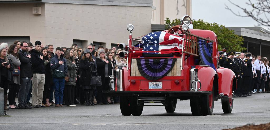 Sequim Gazette photos by Michael Dashiell
Attendees of the Jan. 21 memorial for Capt. Charles Chad Cate look on as the antique fire truck transporting Cates coffin arrives at Sequim High School.