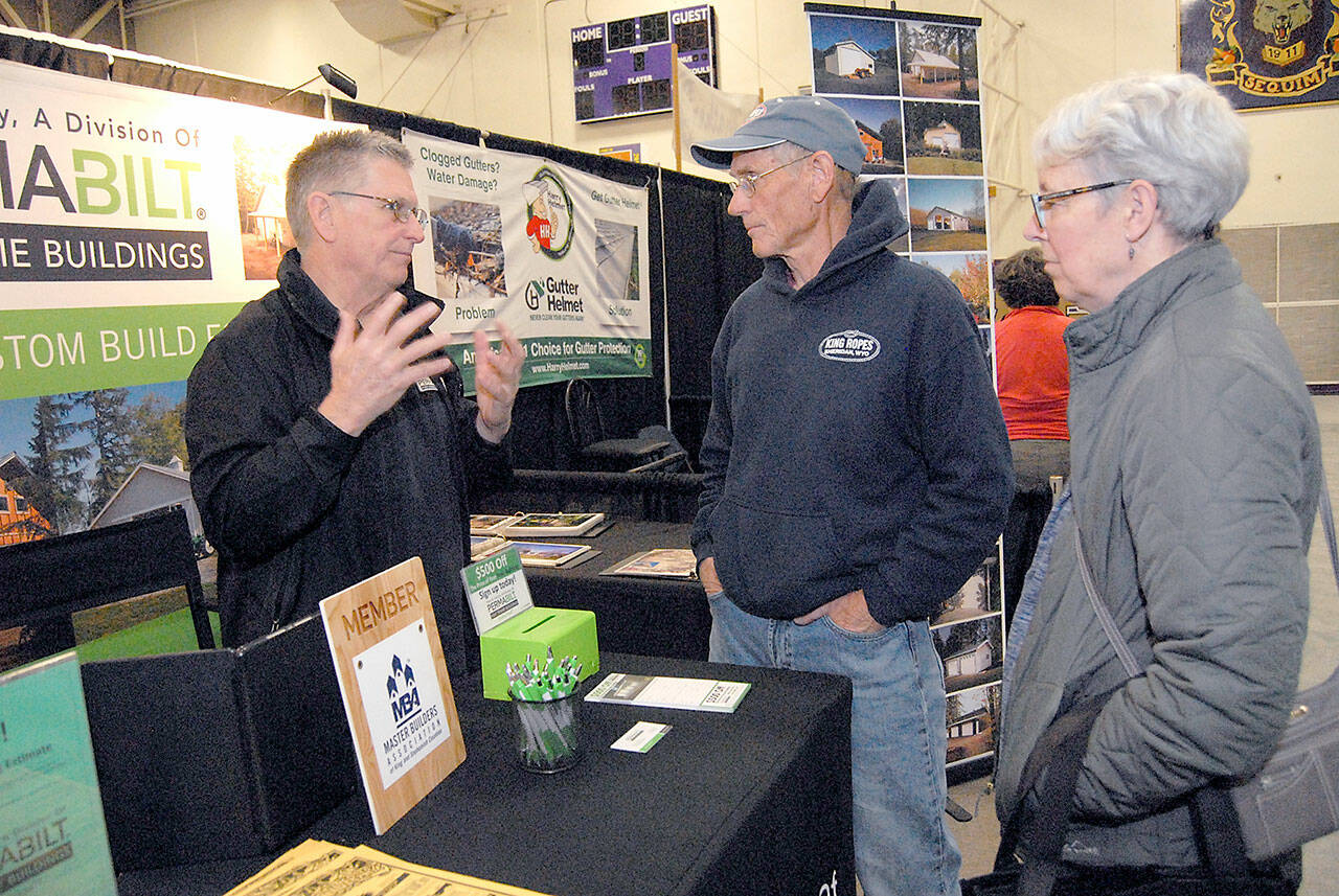 File photo by Keith Thorpe/Olympic Peninsula News Group / Will Johnson of Lynnwood-based PermaBilt Post Frame Buildings, left, speaks with Brad and Marla Varner of Sequim at his companys booth at North Peninsula Building Associations Building, Remodeling and Energy Expo in 2019. NPBA hosts a LEGO building challenge at this years event, set for Feb. 19.
