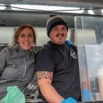 Sequim Gazette photo by Emily Matthiessen / Opal Joy Ruddock and her son Max Unruh, hand take out to customers from the window of the Da Kindz Island Grill food truck.