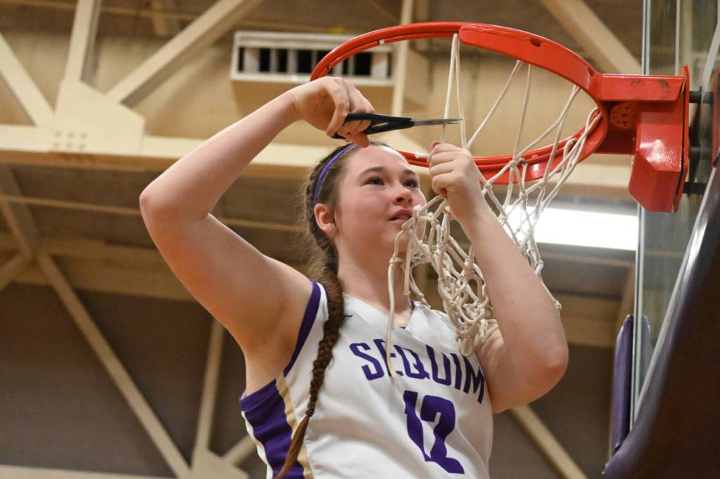 Sequim Gazette photo by Michael Dashiell / Sequims Sammie Bacon joins teammates in a celebratory net-cutting following a 57-46 win over rival Port Angeles last week, as the Wolves finished their Olympic League season at 14-0.