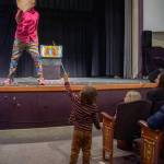 A small child emerges from the audience after the Zaniac ran through with an oversized palm at the end of a rod, high-fiving numerous audience members. The child waits with outstretched hand until Zerbe changes his back hand for a front hand and high-fives the child from the stage. Other children then approach and he jokes about setting a dangerous precedent. Zerbe said that in addition to working hard at something you love, children should look for role models who are successful at what they would like to become skilled at, saying, You have to push yourself – keep pushing the limit – and find people who are better than you (to learn from).