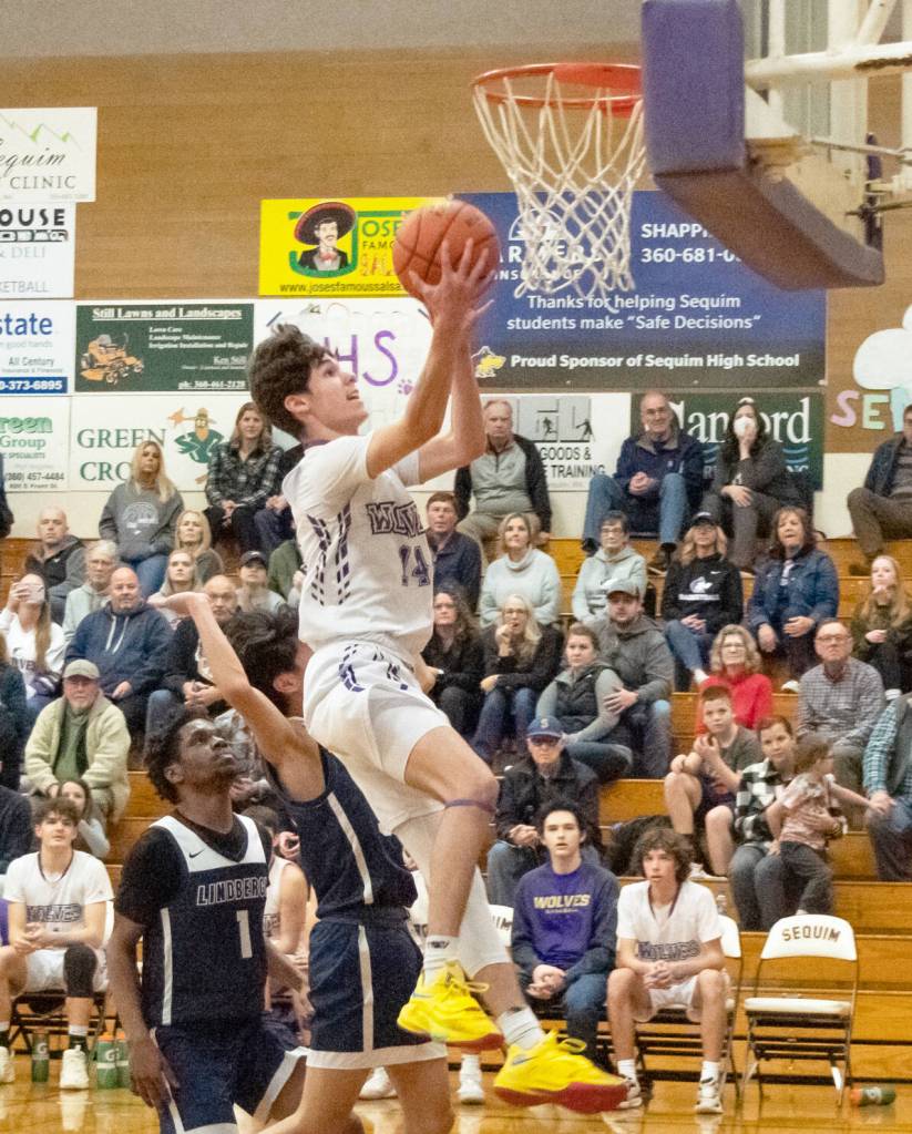 Sequim Gazette photo by Emily Matthiessen / Sequims Vince Carrizosa, center, drives past Lindberghs Gabriel Thomas (1) for a score in the Wolves 66-37 West Central District tournament playoff win on Feb. 15.