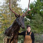 Photo courtesy of Molly Omann 
Olympic Peninsula artist Molly Omann stands near a 9-foot-tall elk she created from driftwood.
