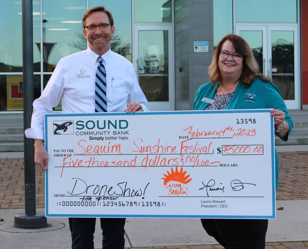 Photo courtesy of City of Sequim / Sequim City Manager Matthew Huish accepts sponsorship funds from Shelli Robb-Kahler, Sound Community Bank Senior Vice President/Relationships Manager, for the Sequim Sunshine Festivals expanded drone show set for March 4.