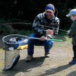 Craig Larson helps his 3-year-old son Barrett net a rainbow trout during Kids Fishing Day on April 23. It was Barrett’s first catch ever, Larson said. (Matthew Nash/Olympic Peninsula News Group)