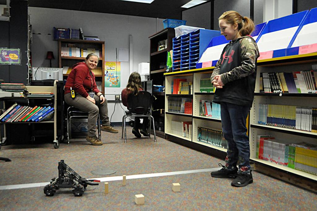 Sequim Gazette photo by Matthew Nash/ Raeani Schierer, right, gives direction to Madelynn McIntyre, sitting in chair, to control a rover on Mars (A.U.R.O.R.A.  Assisted User Remote Operated Robot Arm) as Katie Wilkinson, a substitute paraeducator, watches. The pair were practicing a week prior to their classrooms mission to Mars on March 27.