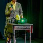 Sequim Gazette photo by Emily Matthiessen / Ann Burland plays a small role as presenter Brenda Hulse in Calendar Girls, an OTA production based on the true story of a group of Yorkshire women and a local professional photographer who produce a discretely nude calendar to raise money for cancer research 24 years ago. Currently they have raised more than 6 million pounds.