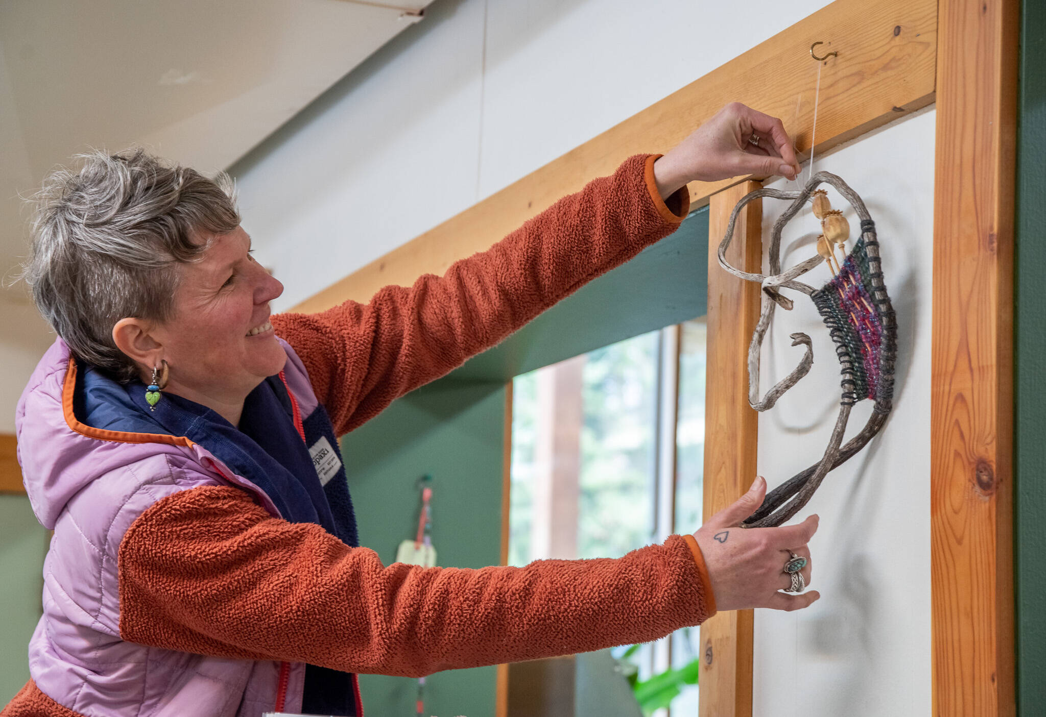 Sequim Gazette photo by Emily Matthiessen 
Artist Emily Carlquist adjusts one of her abstract pieces featuring weaving on a kelp root with poppies at Dandelion Botanical Company at 4681 Sequim-Dungeness Way, where Carlquist is the featured artist for the month of April.