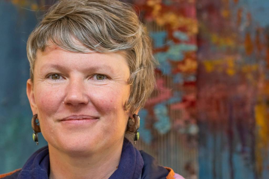 Sequim Gazette photo by Emily Matthiessen / Artist Emily Carlquist, seen here before one of her abstract multi-media pieces featuring acrylic paint on textured canvas with needle-woven local fiber warped on canvas, on display at Dandelion Botanical for the month of April.