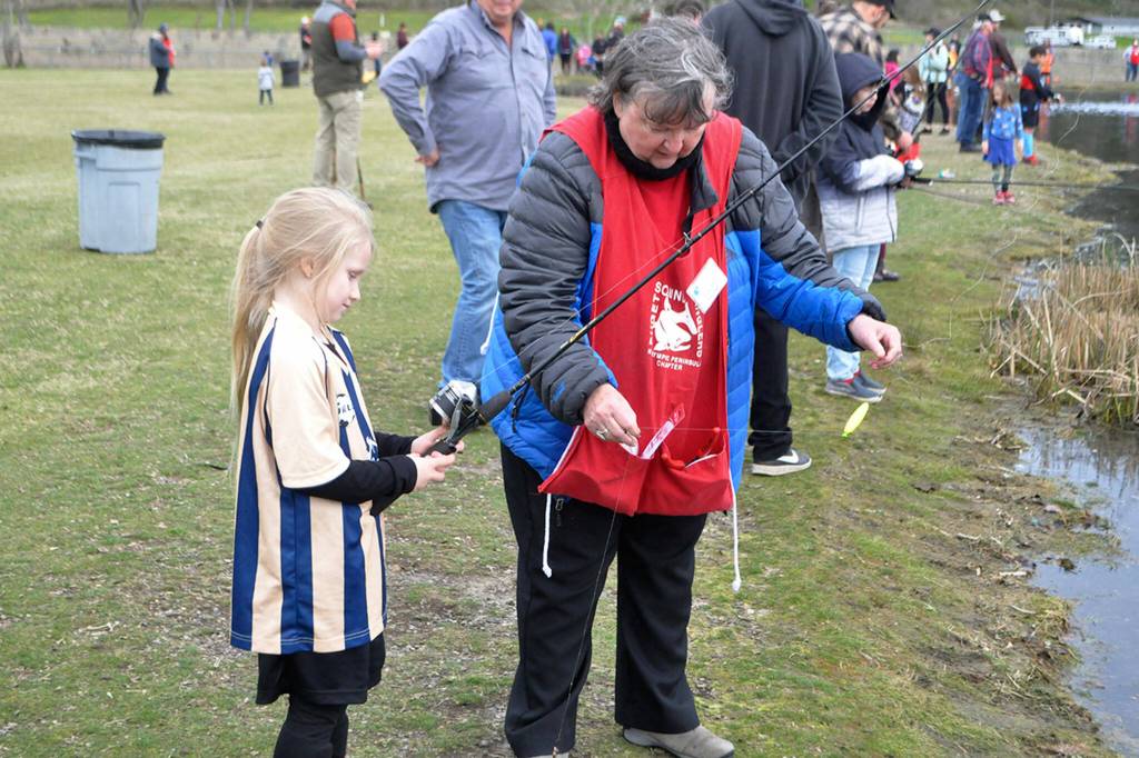 Volunteer Claudia Eklund with the Puget Sound Anglers helps Zayleigh McCullem put a worm on her hook on April 22.