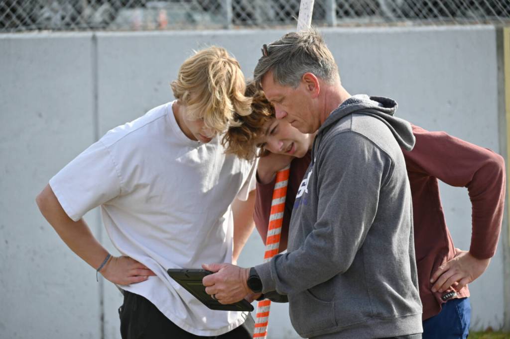 From left, Sequims Mirek and Ari Skov look over a video review of a vault with SHS coach Brad Moore at a practice last week.