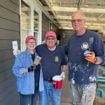 Sequim Gazette photo by Matthew Nash/ Sequim Sunrise Rotary volunteers, from left, Becki Roberts, Chris Coolures, and Eric Mahnerd are all smiles as they continue to paint the exterior of a Sequim home for a mother and her son. Mahnerd said Rotarians and Habitat for Humanity volunteers had 134 hours into the project leading up to Saturdays Sequim Beautiful Day event, and they anticipate about another 50 hours to finish repairs and replace the deck. <ins>The trio are also nicknamed Little Ladder, Short Ladder, and Tall Ladder, they said. </ins>