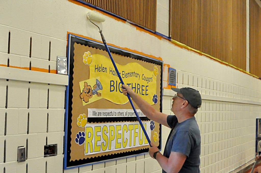 Tim Richards, lead pastor with Dungeness Community Church, helps paint a wall inside Helen Haller Elementarys cafeteria.