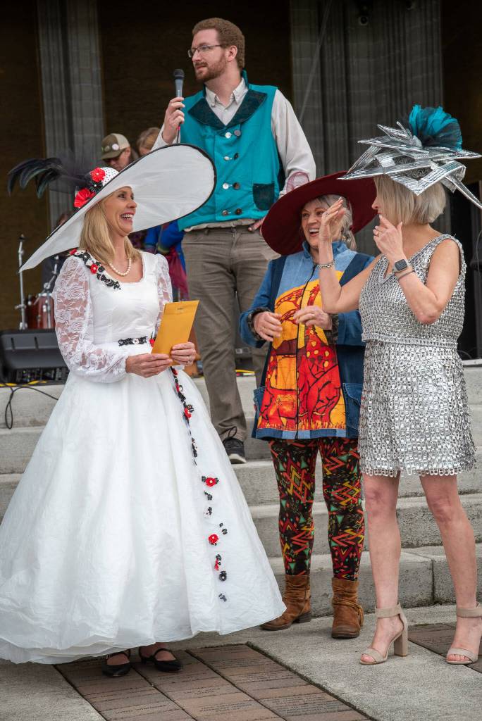 Sequim Gazette photo by Emily Matthiessen / In the festival's first annual Trashion Show, Cherie Hendrickson, left, modeled the winning dress, designed by Cherry Bibler. The dress, made from Walmart plastic bags, recycled plastic and thrifted sheets, was revealed by Hendrickson to be reversible in a dramatic moment. Above Hendrickson is emcee Conor Dawley and left, models Kim Pratt and Trisha Cobb.