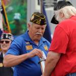 Kevin ONeal of Sequim VFW Post 4760 places a challenge coin in the time capsule at the dedication of Olympic Peninsula Academys flagpole on May 18.