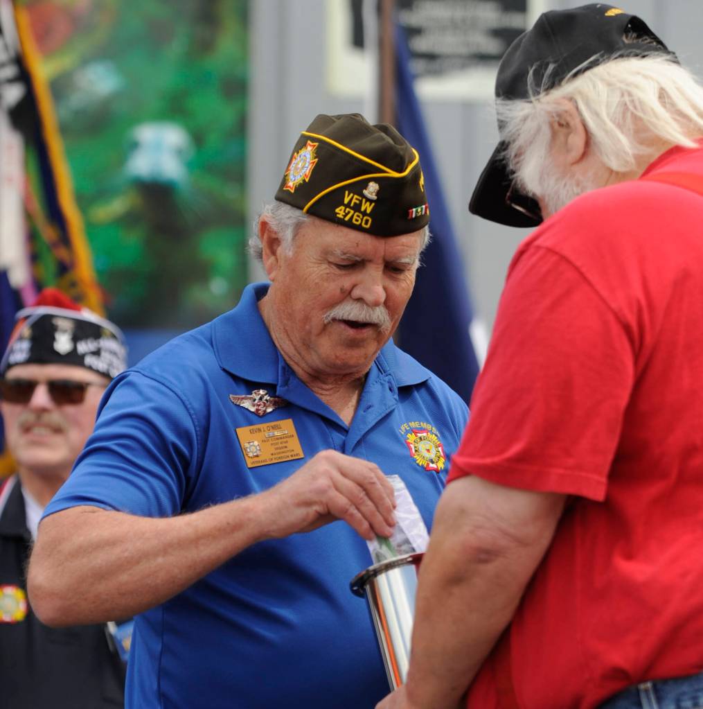 Kevin ONeal of Sequim VFW Post 4760 places a challenge coin in the time capsule at the dedication of Olympic Peninsula Academys flagpole on May 18.