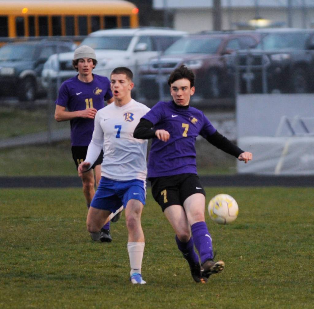 Sequims Colin Feik, right, passes to a teammate in a March 30 Olympic League match-up.
