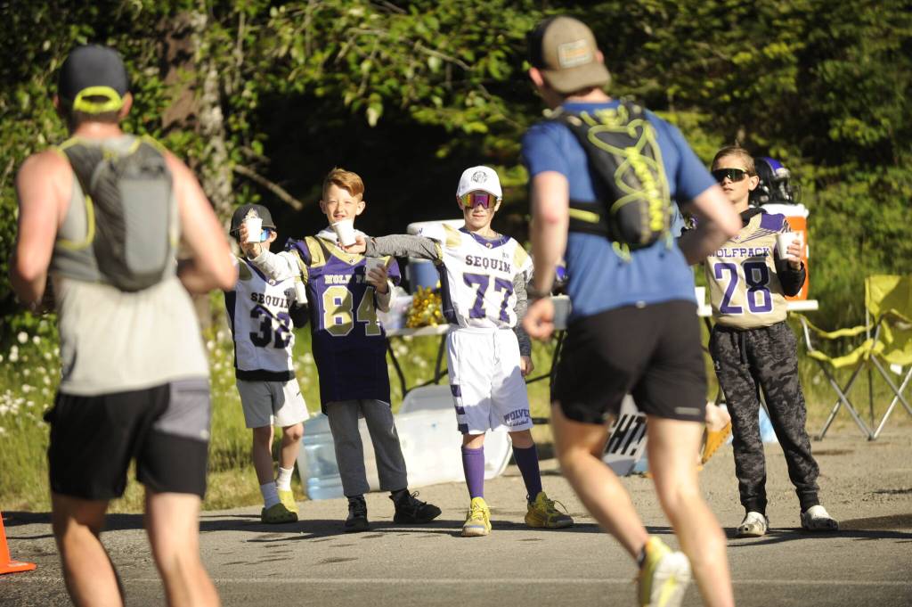 Members of the Sequim Wolfpack youth football team hand out water to North Olympic Discovery Marathon runners at an aid station off Whitefeather Way on June 4.