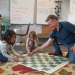 Lucian Churchill and Aspen Slife help chess coach Derek Slife clean up after Five Acre Schools first chess tournament.