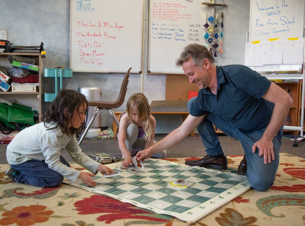 Lucian Churchill and Aspen Slife help chess coach Derek Slife clean up after Five Acre Schools first chess tournament.