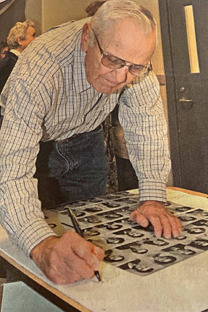 Sequim Gazette file photo by Matthew Nash/ Jerry Angiuli signs a commemorative picture at the 60th class reunion of the Sequim High School Class of 1950.