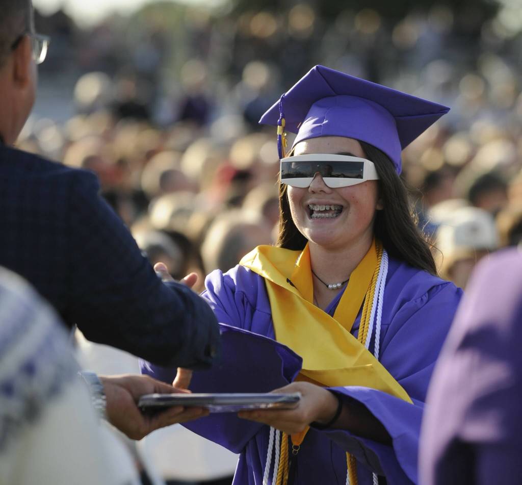 Sequim Gazette photo by Michael Dashiell / Hannah Bates is all smiles as she receives her diploma from school board member Michael Rocha Friday evening. Bates was wearing the same sunglasses her brother wore to graduation.
