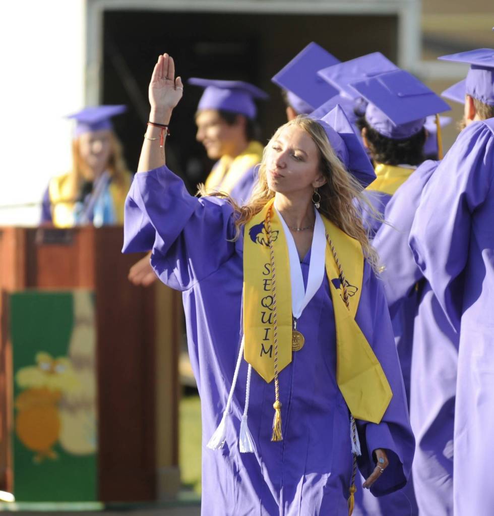 Sequim Gazette photo by Michael Dashiell / Hiilei Robinson offers a parting wave as she and fellow Sequim High seniors accept diplomas at the schools graduation ceremony on June 16.