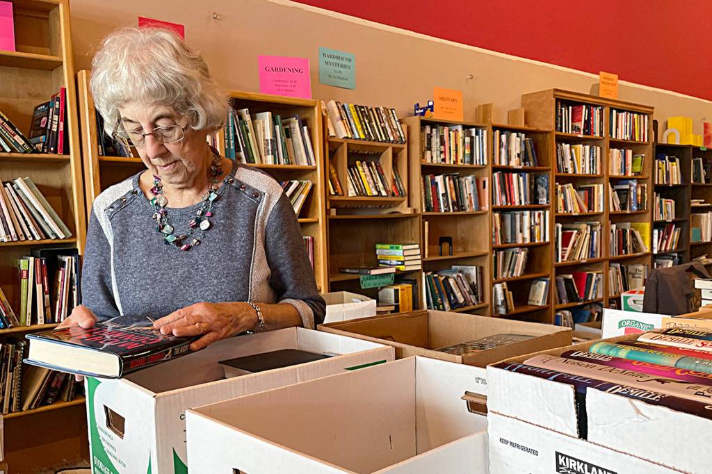 Sequim Gazette photo by Matthew Nash/ Nancy Drew, a long-time volunteer, sorts books on June 14 in Rock Plaza where the Friends of Sequim Library host their monthly book sale.