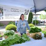 Photo by Michael Dashiell / Lindsey Soha greets customers at the Rhea Sunshine Farm booth at the Sequim Farmers Market in mid-May.