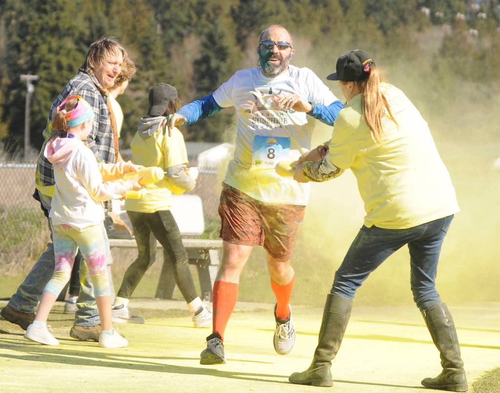 Sequim Gazette file photo by Michael Dashiell. Russ Britton gets a splash of color from volunteers at the Sun Fun Color Run 5k at the Albert Haller Playfields in 2022.