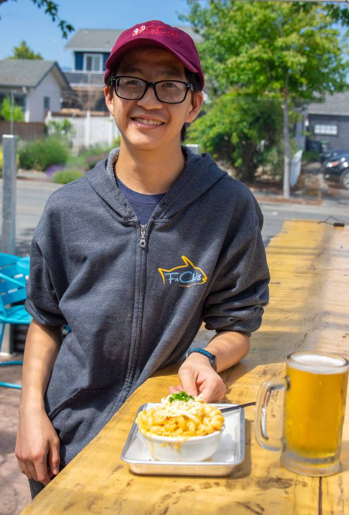 Ethan Cesena, a recent hire at FnChips, serves a helping of macaroni and cheese with crab, made from scratch at FnChips in the outside dining area. The dish is also available with smoked salmon.