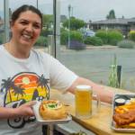 Sequim Gazette photo by Emily Matthiessen / Long-term employee Maria Flores-Lewis serves a helping of clam chowder in a bread bowl and fish and chips with coleslaw and tartar sauce in the outside seating area of FnChips. Maria is amphibious, say Salty Girls owners Tracie Millet and Lavon Gomes, she helps wherever she is needed. The owners say that employees high morale is the force behind Salty Girls success.