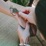 Photo courtesy of Sequim Farmers & Artisans Market/SFAM / Patience Edwards applies a henna flower tattoo to a customer at the Wild Feather Henna booth.